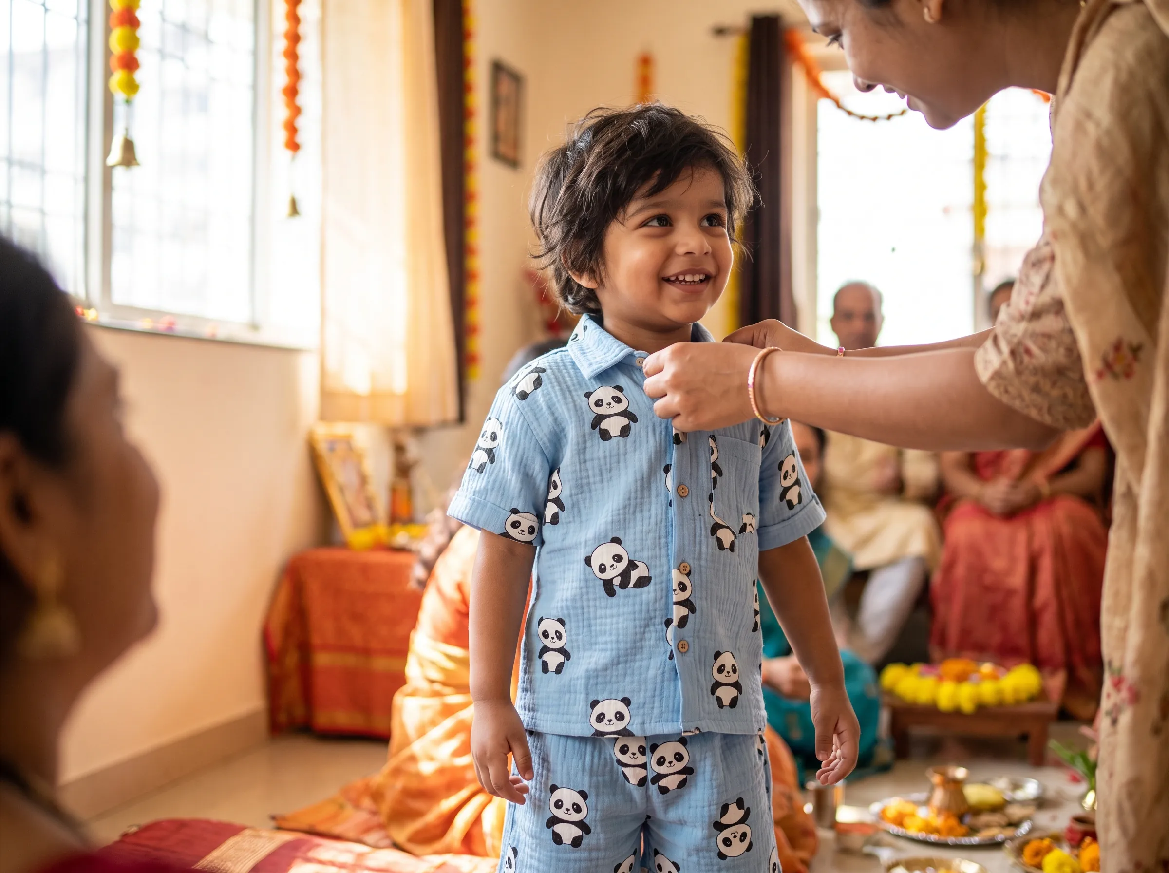 Smiling child wearing sky blue muslin co-ord set with panda print, festive Raksha Bandhan setting