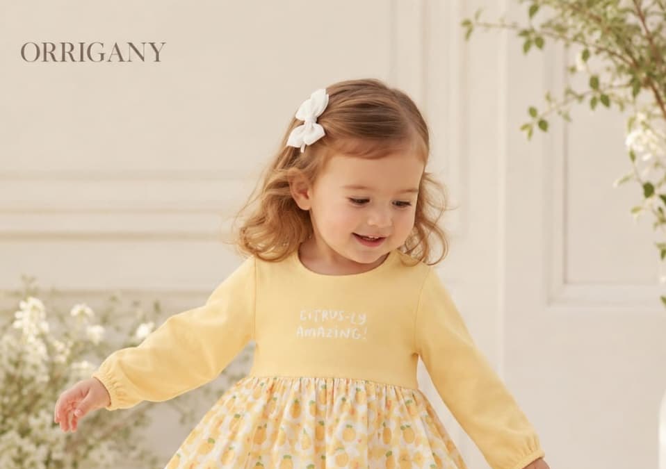 Baby girl in an Orrigany yellow pineapple print cotton dress, smiling