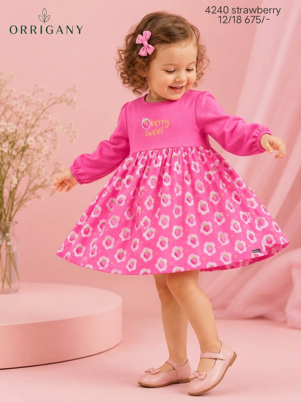 Baby girl in an Orrigany pink strawberry print cotton dress smiling